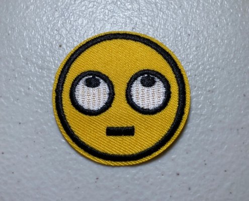 a round patch in yellow thread embroidery rolling eyes u in black