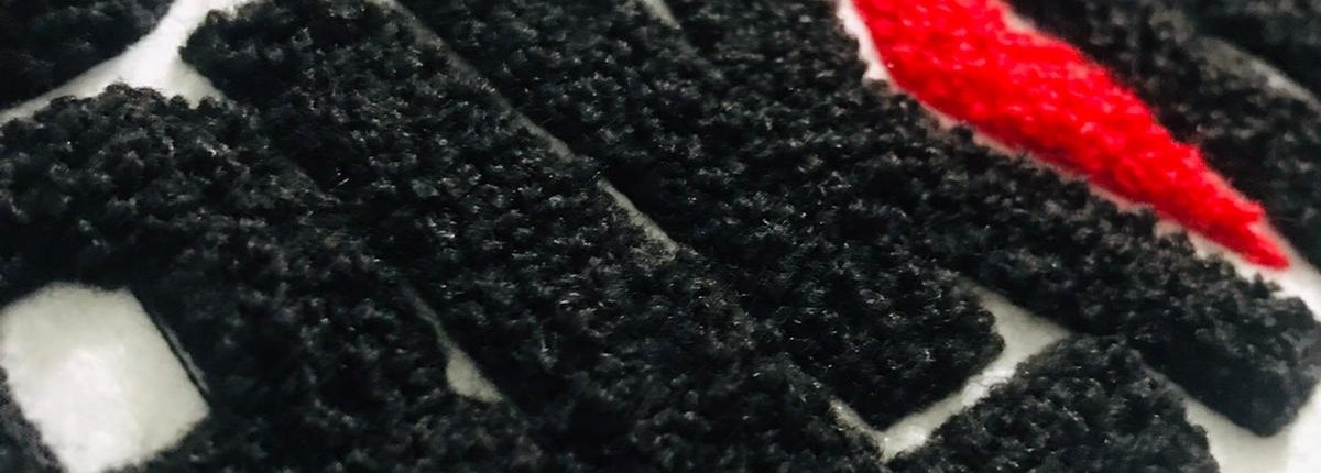 a close look of a chenille patch shows multi color yarn representing Jamaican culture