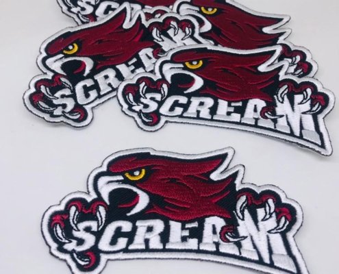 a 4 inches wide custom embroidery patch in maroon thread eagle die cut shape with white sating letters under paw that says SCREAM for a baseball jersey and hat to stick on using heat seal iron on backing glue on the back